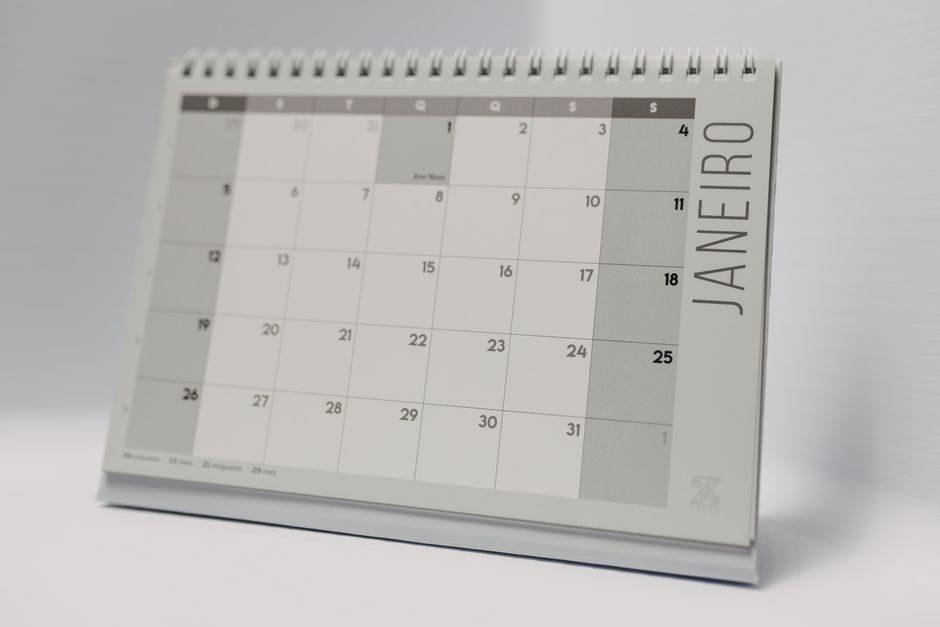 Desk calendar showing the month next to a laptop, used for time-blocking a Notion task list